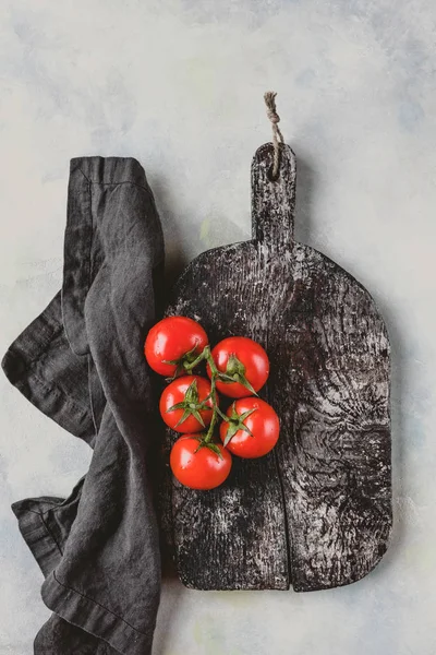 Top view of kitchen towel, cutting board and cherry tomatoes on marble table — Stock Photo