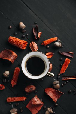 Kuru otlar ve koyu ahşap masa üzerinde kahve çekirdekleri ile sıcak kahve