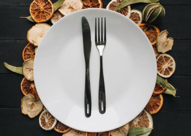 Beyaz tabak, bıçak ve çatal kuru meyve dilimleri üzerinde 