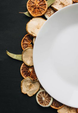 Kuru meyve dilimleri üzerine beyaz tabak, kış süslemesi.