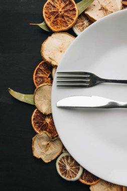 Beyaz tabak, bıçak ve çatal kuru meyve dilimleri üzerinde 