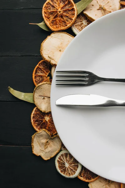 Beyaz tabak, bıçak ve çatal kuru meyve dilimleri üzerinde 