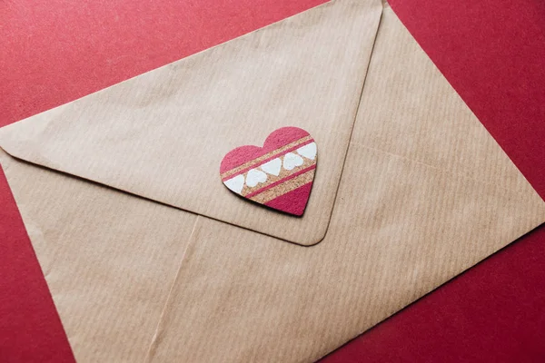Valentines day craft envelope with decorative handmade heart on red background