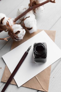 dizi vintage DIP kalem, inkpot, boş kağıt sayfası, beyaz tahta masada zarf ve pamuk şube