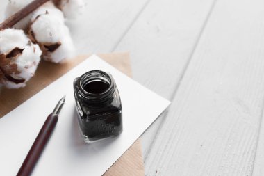 dizi vintage DIP kalem, inkpot, boş kağıt sayfası, beyaz tahta masada zarf ve pamuk şube