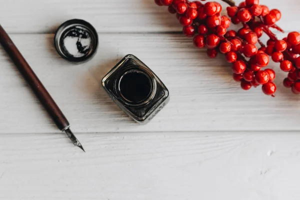 红莓装饰白木桌上的老式蘸笔和 Inkpot — 图库照片