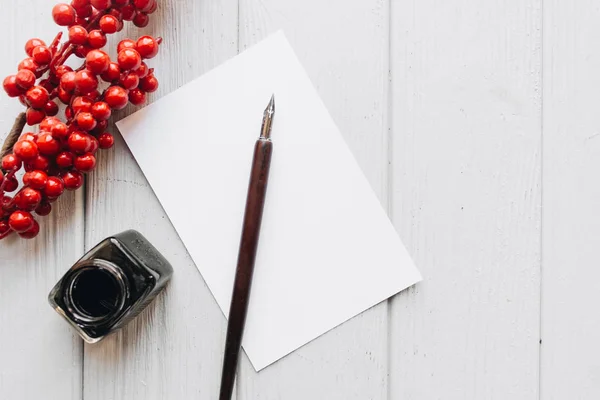 一套老式的蘸笔 墨水和空白的纸表上的白色木桌与红色浆果 Deocration — 图库照片