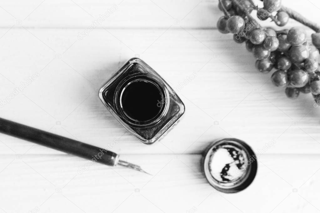 set of vintage dip pen and inkpot on white wooden table with berries decoration, black and white
