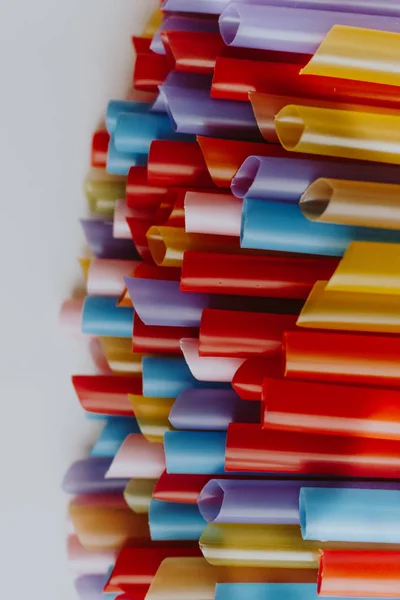 pile of colorful cocktail straws over white background