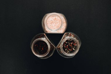 cam kutu aromalı tuz, çeşitli peppercorns ve siyah arka plan üzerinde kırmızı baharat