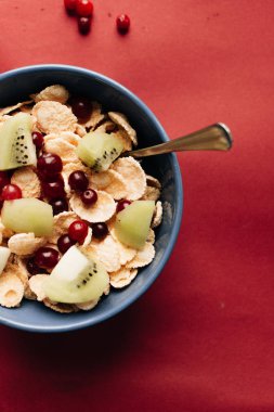 kivi parçaları ve kızılcık kase, kırmızı zemin üzerine sağlıklı kahvaltı lezzetli çıtır Mısır gevreği