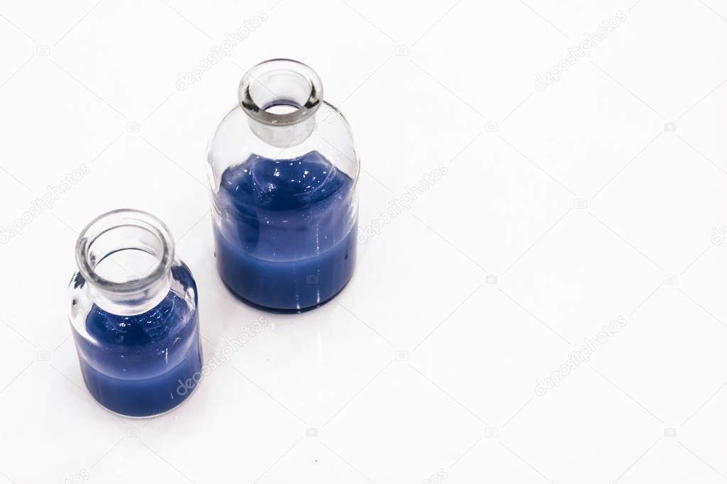 two glass jars with blue liquid isolated over white background