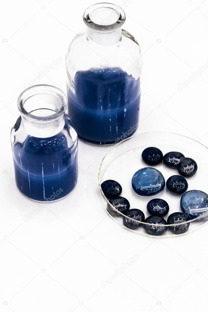 two glass jars with blue liquid and blue small stones isolated over white background
