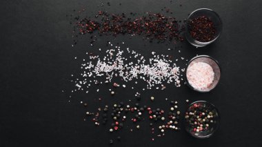 gözlük aromalı tuz, çeşitli peppercorns ve siyah arka plan üzerinde kırmızı baharat