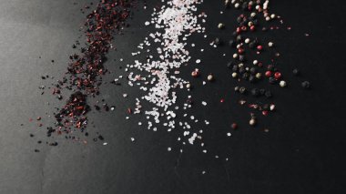 tuz, çeşitli aromalı karabiber ve kırmızı baharat siyah arka plan üzerine dağılmış