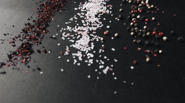 tuz, çeşitli aromalı karabiber ve kırmızı baharat siyah arka plan üzerine dağılmış