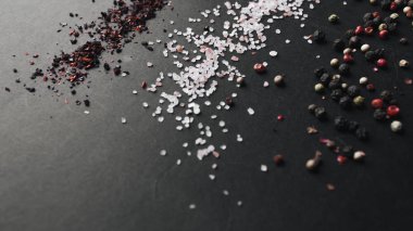tuz, çeşitli aromalı karabiber ve kırmızı baharat siyah arka plan üzerine dağılmış