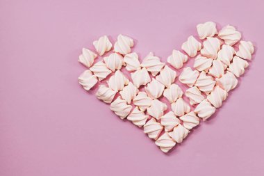 Lila zemin üzerine lezzetli tatlı şekerleme yığını kalp şeklinde