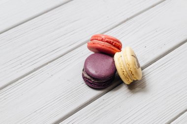 Beyaz ahşap masa, tatlı tatlı üzerinde üç lezzetli renkli bademli kurabiye 