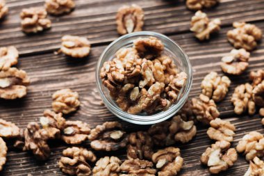 Kabuklu ceviz ahşap zemin, sağlıklı beslenme kavramı üzerine cam küçük kapta yığını