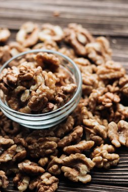 Kabuklu ceviz ahşap zemin, sağlıklı beslenme kavramı üzerine cam küçük kapta yığını