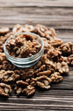 Kabuklu ceviz ahşap zemin, sağlıklı beslenme kavramı üzerine cam küçük kapta yığını