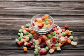 pile of sweet colorful candied fruits in small glass bowl on wooden table