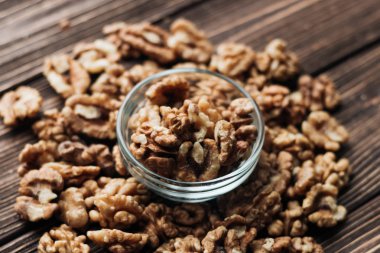 Kabuklu ceviz ahşap zemin, sağlıklı beslenme kavramı üzerine cam küçük kapta yığını