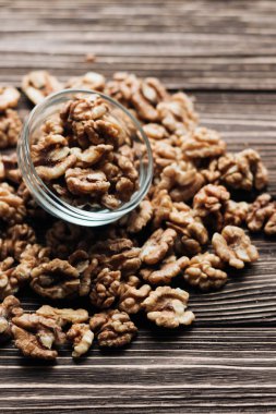 Kabuklu ceviz ahşap zemin, sağlıklı beslenme kavramı üzerine cam küçük kapta yığını