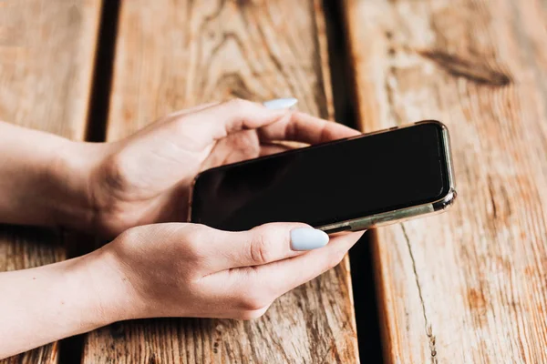 Kvinna Som Håller Smartphone Mot Träbord — Stockfoto