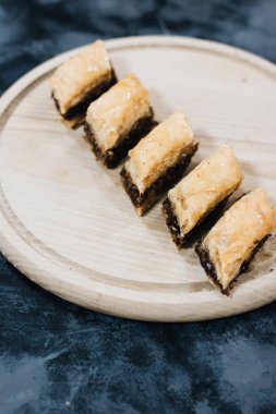 Baklava tatlı tatlı ahşap tahta üzerinde. Kıyılmış fındık ile dolu ve şekerli ve şurubu veya bal ile birlikte düzenlenen filo kat pasta yaptı