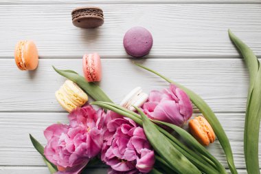 lezzetli renkli macaroons ve üzerinde beyaz ahşap masa, tatlı tatlı Pembe Laleler 
