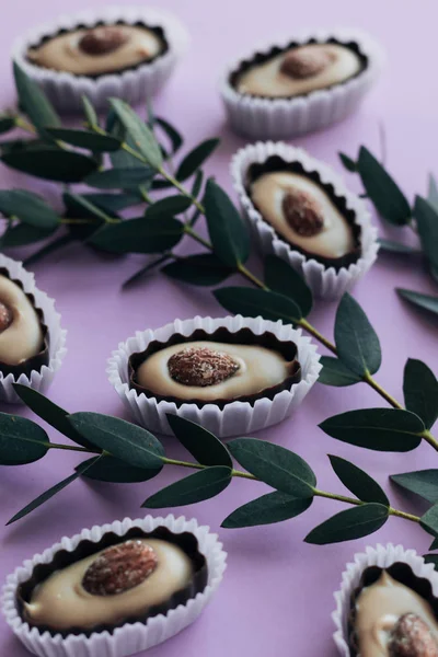 Composição Deliciosos Doces Pralinos Com Amêndoas Galhos Verdes Fundo Roxo — Fotografia de Stock