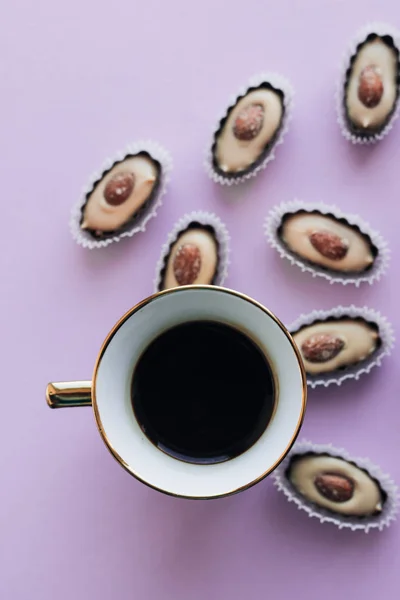 커피와 자주색 배경에 아몬드로 프랄린 — 스톡 사진