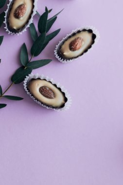 lezzetli pralin tatlı badem ve mor zemin üzerine yeşil dallar ile kompozisyon