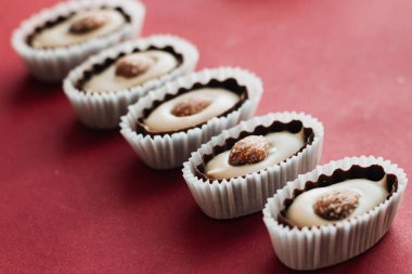 satır kırmızı zemin üzerine badem ile lezzetli pralin tatlılar