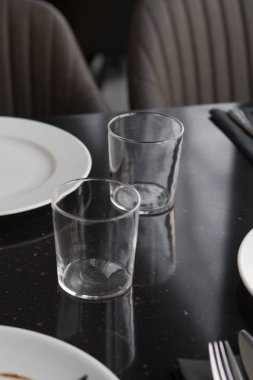 Beyaz tabaklar, gözlük ve siyah tablo, zarif sofra gereçleri 