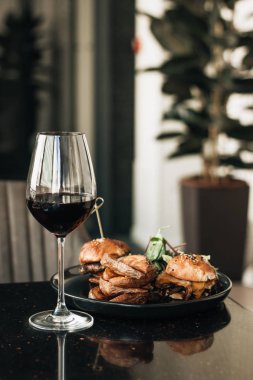 kırmızı şarap, burgers ve fries kafede masada ile bardağı 