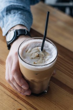 Erkek el lezzetli cappucino bardak kahve ahşap masa üzerinde tutarak 