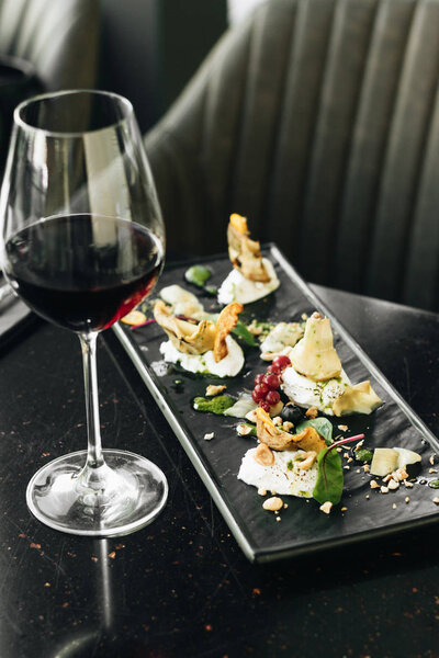 wineglass with red wine and antipasti set on table in cafe 
