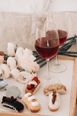 çeşitli lezzetli tatlılar, kırmızı şarap ve Düğünçiçeği çiçekli kadehlerin 