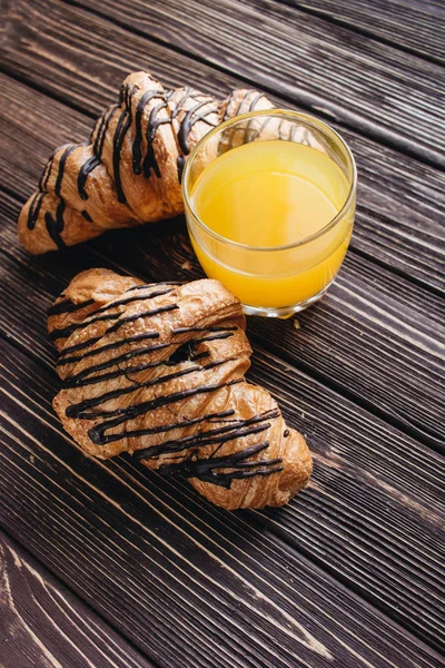 delicious sweet croissants on wooden table and glass of orange juice, delicious homemade dessert