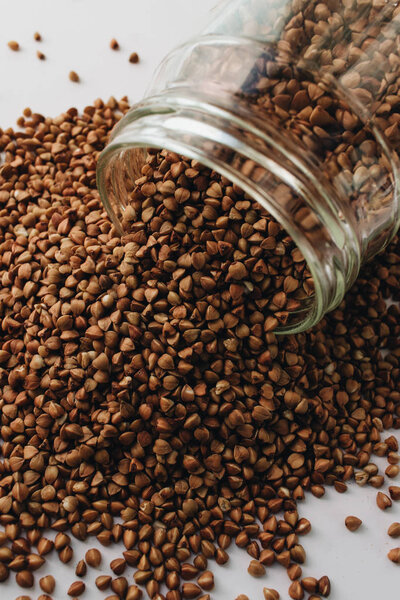 raw buckwheat in glass on white background