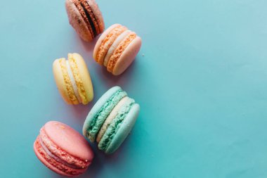 Mavi arka planda lezzetli renkli badem kurabiyelerinin kompozisyonu 