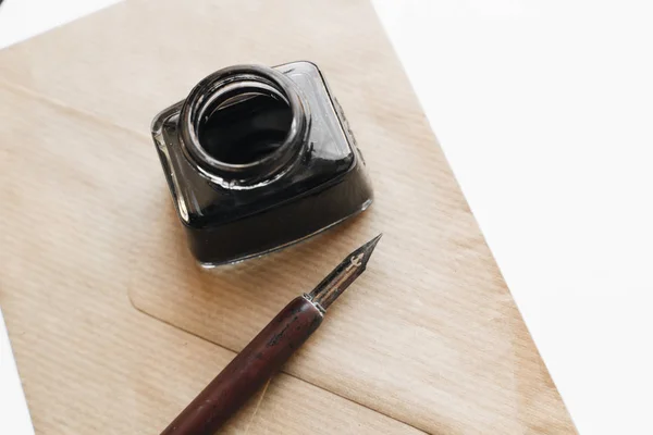 set of vintage dip pen, inkpot and envelope on white wooden table