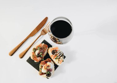 Yumurtalı, somonlu, zeytinli ve etli nefis bruschettalar geleneksel İtalyan mutfağı, beyaz masadaki malzemeler.