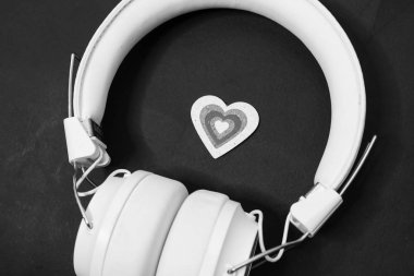 heart symbol and white modern headphones on black background