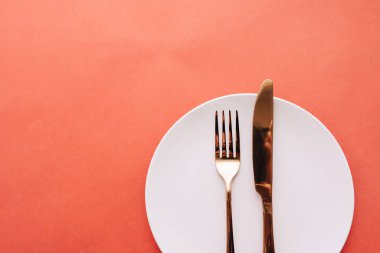 Beyaz tabak, çatal, kırmızı masada bıçak, zarif sofra takımı. 