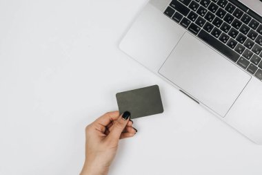 Kredi kartı tutan ve dizüstü bilgisayar kullanan eller. İnternetten alışveriş 