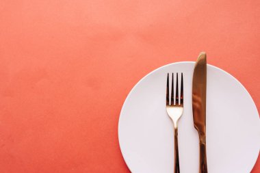 Beyaz tabak, çatal, kırmızı masada bıçak, zarif sofra takımı. 